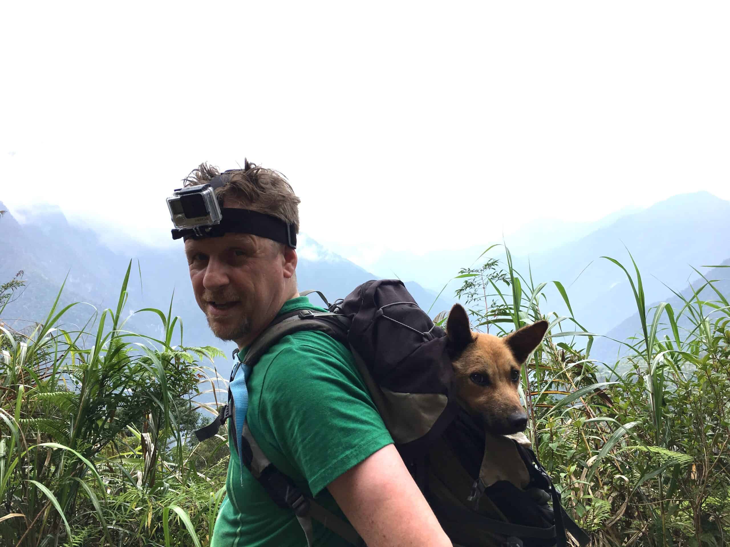 StrayKind founder Sean McCormack carrying a rescued stray dog in a backpack through the mountains of northern Taiwan